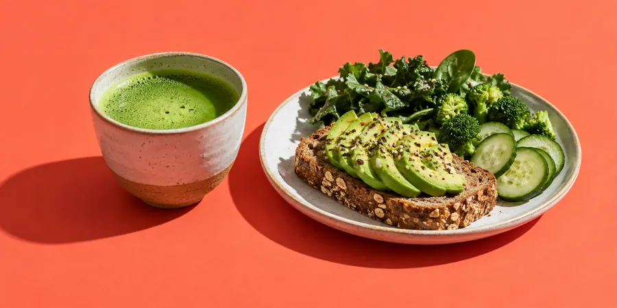 Kopp matcha på ett bord bredvid en tallrik med fullkornsbröd