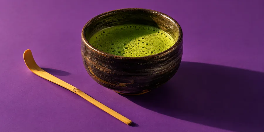 Skål med matcha i varmt kvällsljus mot violett bakgrund