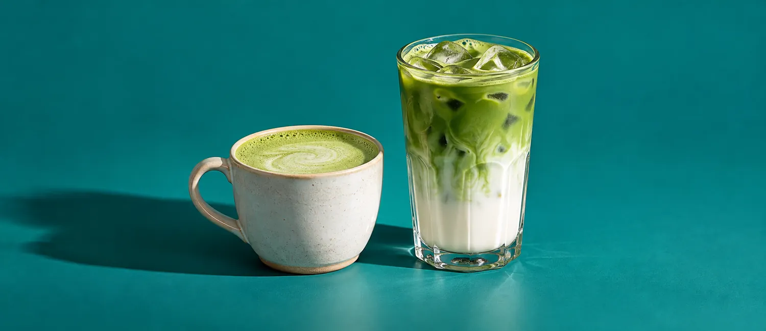 Varm matcha latte i kopp och matcha islatte i glas med isbitar mot turkos bakgrund