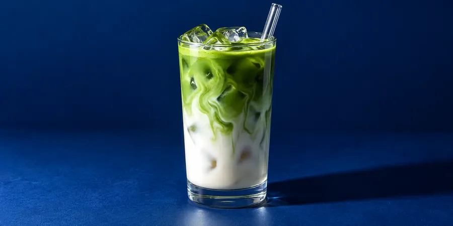 Matcha islatte i högt glas med isbitar och gröna och vita lager